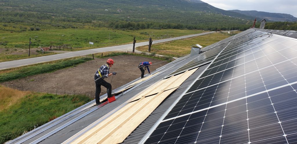 to perosner monterer solceller på et tak