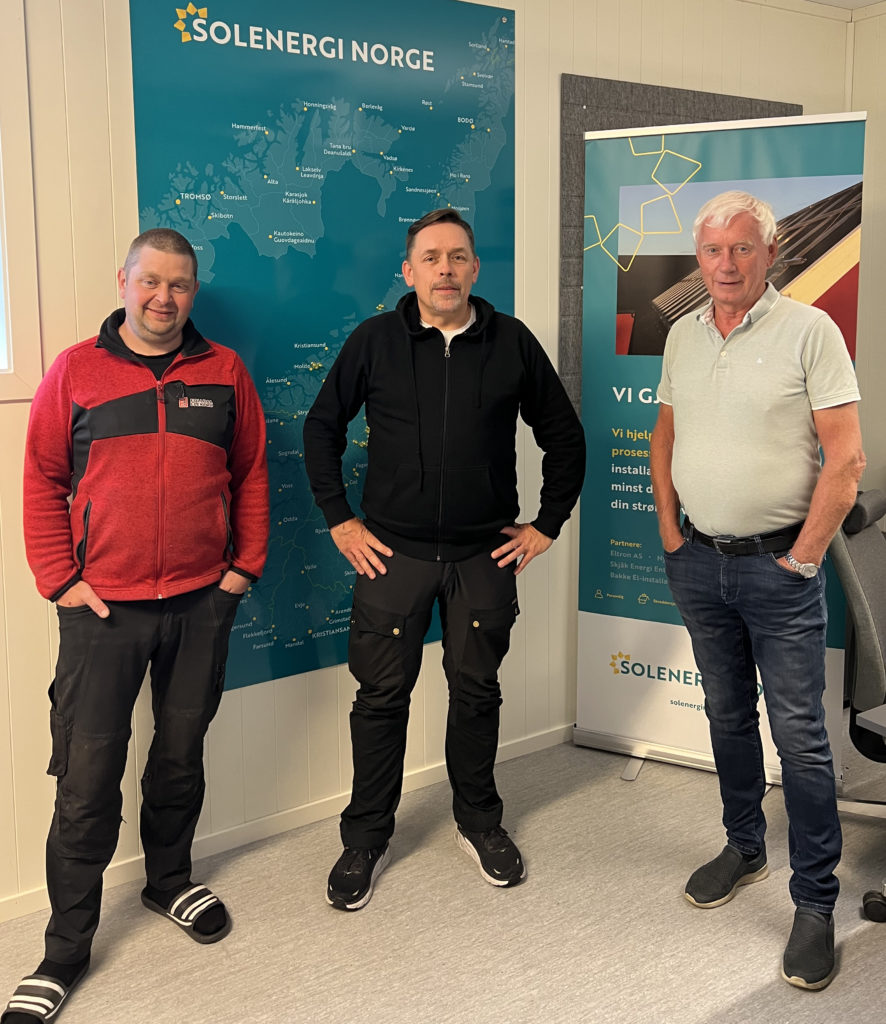 tre menn poserer foran et norgeskart og en roll up med solenergi norge-informasjon