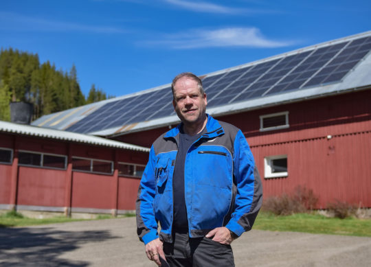 Neslund foran solcelleanlegg montert på låvetaket